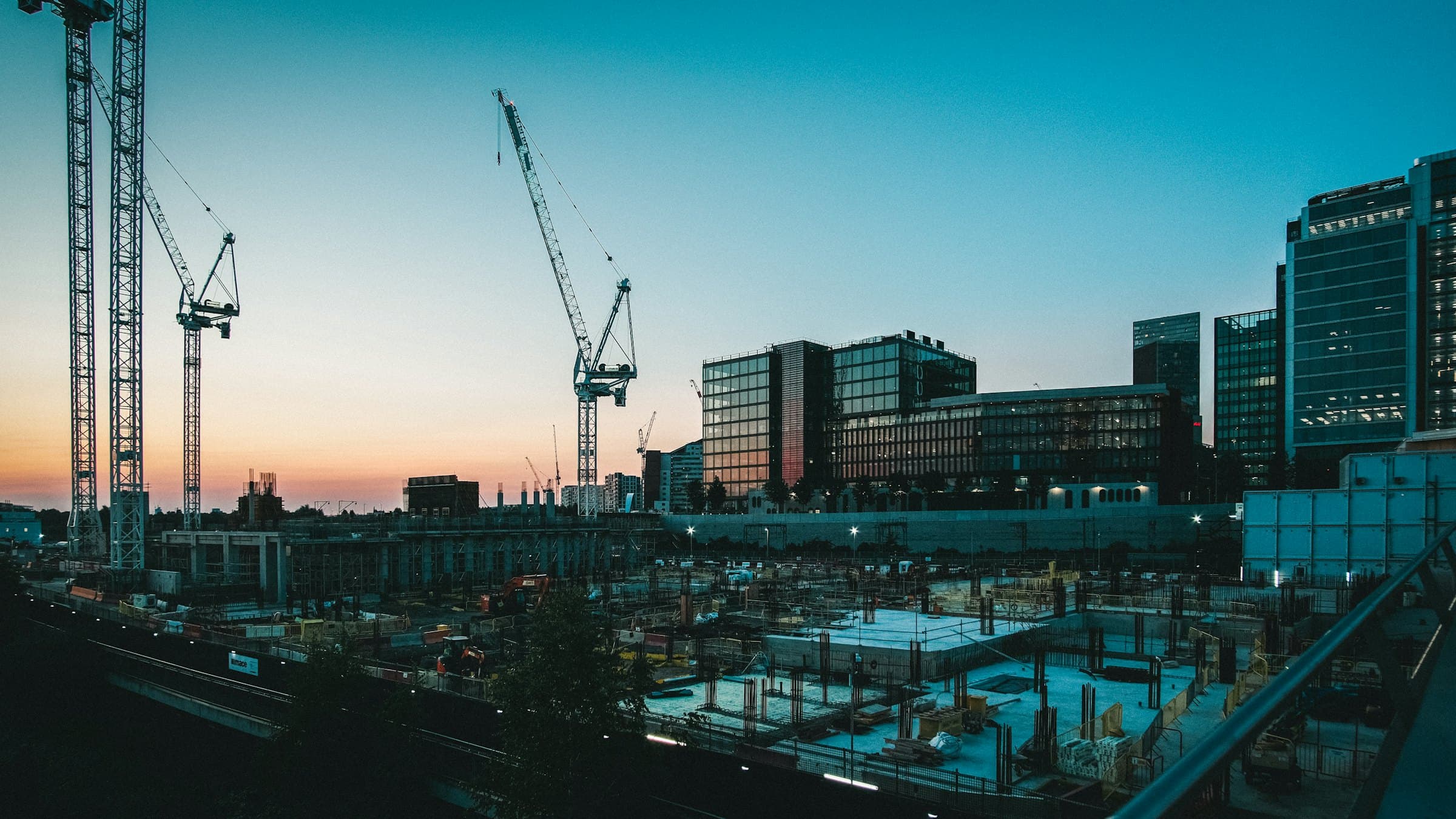 Construction site at dusk with tower cranes and buildings under construction